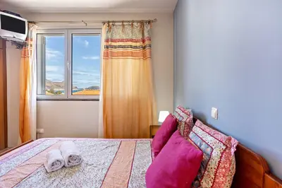 a bedroom with a bed with a window and towels at Sonho Dourado Apartamento de praia in Porto Santo