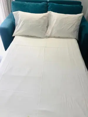 a bed with two white pillows and a blue couch at A Cornes Of The Atlantic in Funchal