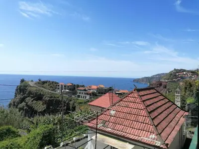 a chair on a balcony with a view of the ocean at Westerland House in Ribeira Brava