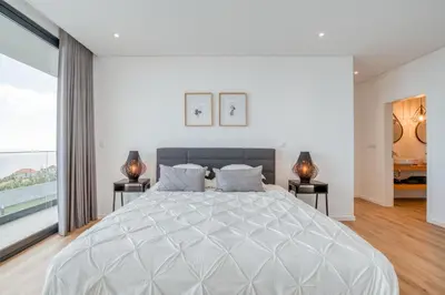 a white bedroom with a large bed and two lamps at Vila Inanda in Ponta do Sol