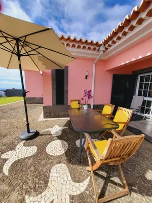 a patio with a table and chairs and an umbrella at Villa Paradise Madeira Ocean View in Fajã da Ovelha