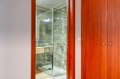 a glass shower in a room with a wooden door at Forum Escape, a Home in Madeira in Funchal