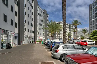 a street with cars parked in a parking lot with palm trees at Forum Escape, a Home in Madeira in Funchal