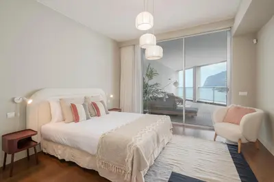 a bedroom with a bed and a chair and a large window at Madeira Palace I by An Island Apart in Funchal