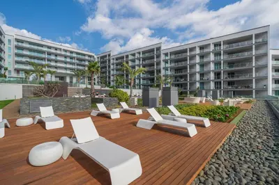 a patio with white furniture in front of a building at Madeira Palace I by An Island Apart in Funchal