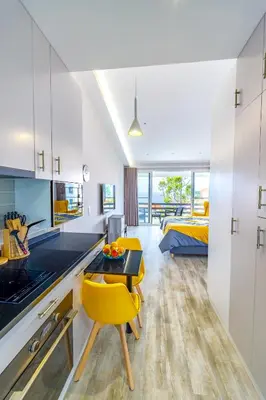 a kitchen with a table and yellow chairs in a room at Vista Oceano III in Caniço