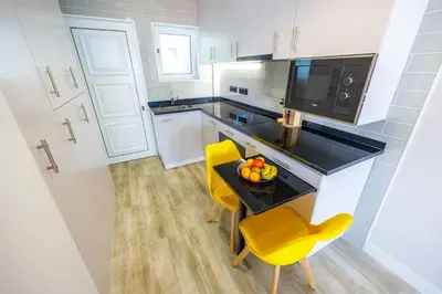 a small kitchen with a table and yellow chairs at Vista Oceano III in Caniço