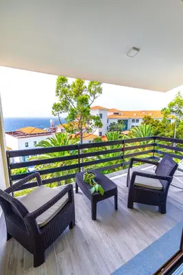 a balcony with chairs and tables and a view of the ocean at Vista Oceano III in Caniço