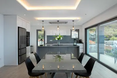 a kitchen and dining room with a table and chairs at SKYFALL VILLA in Arco da Calheta
