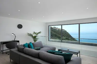 a living room with a couch and a large window at SKYFALL VILLA in Arco da Calheta