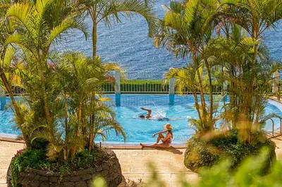a woman sitting in a swimming pool with palm trees at Quinta da Falésia II by An Island Apart in Funchal