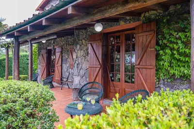 a patio with chairs and tables and a stone wall at Villa Achada da Mouca by Homie in Santana