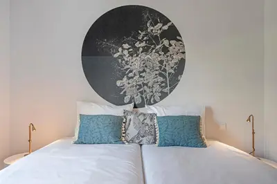 a bedroom with a white bed with a large painting on the wall at Monumental Place by An Island Apart in Funchal