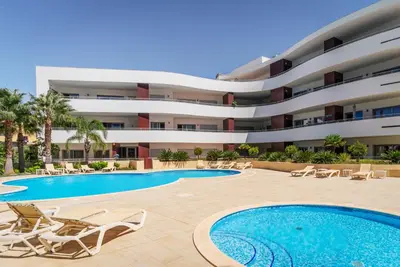 a hotel with a swimming pool and chairs and a building at Spacious 2 bedroom Apartment with Sea View Lagos by Lisbeyond in Lagos