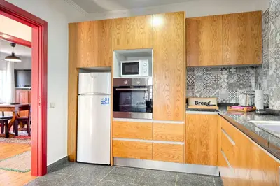 a kitchen with wooden cabinets and a white refrigerator at Os Ferreirinhos, a Home in Madeira in São Jorge