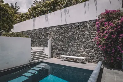 a swimming pool with a bench next to a brick wall at VILLA QUINTA TORRINHA Rooms in Funchal