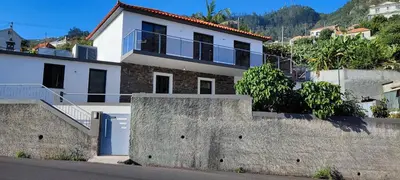 a white house on a hill with a wall at Casa Magic Vieira New well located with services in Arco da Calheta