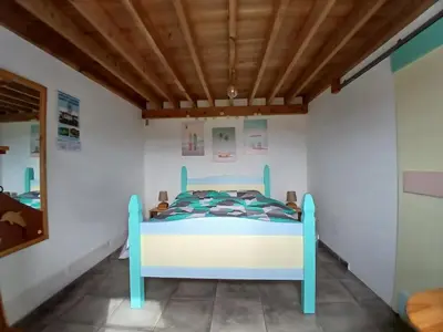 a bed in a room with a wooden ceiling at Casinha do Barreiro - Cosy Private Cottage in Vila do Porto