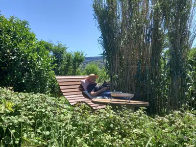 a woman sitting on a hammock in a garden at Casinha do Barreiro - Cosy Private Cottage in Vila do Porto