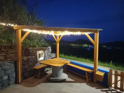 a wooden pergola with a table and a bench at Casinha do Barreiro - Cosy Private Cottage in Vila do Porto
