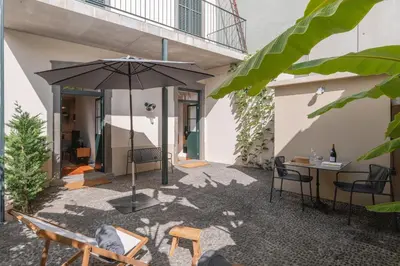 a patio with an umbrella and chairs and a table at OurMadeira - Chill Garden Apartment in Funchal