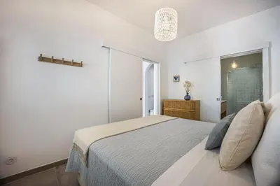 a white bedroom with a bed and a window at Casa Mateus in Vila do Bispo