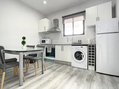 a white kitchen with a table and a washing machine at Casa da Avo by Atlantic Holiday in Caniçal