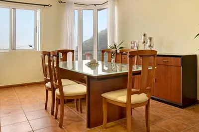 a glass table with two chairs and a table with a plate at Vinháticos House in São Vicente