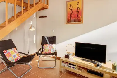 a living room with two chairs and a flat screen tv at Calheta Lofts I in Calheta