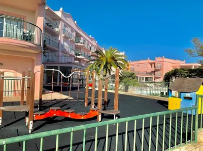 a playground in front of a building with palm trees at Casa Da luz 5 - st james apt 2 bedrooms , Amazing sea view , pool , wifi in Luz