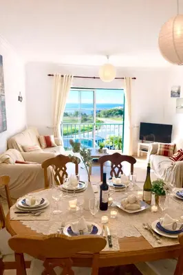 a living room with a table with chairs and a couch at Casa Da luz 5 - st james apt 2 bedrooms , Amazing sea view , pool , wifi in Luz
