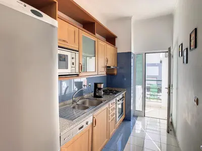 a kitchen with wooden cabinets and a sink at Theos Apartment by LovelyStay in Funchal