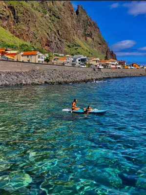 a man and a dog on a surfboard in the water at Home Away From Home in Caniçal