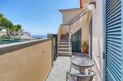 a balcony with two chairs and a table and some stairs at Vilamar 2 - Madeira Inn Group in Calheta