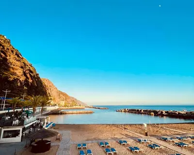a beach with lounge chairs and the ocean at Vilamar 2 - Madeira Inn Group in Calheta