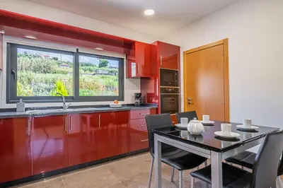 a kitchen with red walls and a table and chairs at Canhas Residence I by Homie in Ponta do Sol