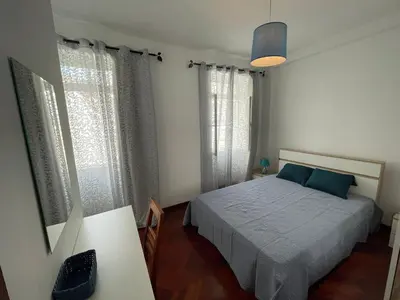 a bedroom with a bed and a table and windows at Fort Traditional Guest House in Funchal