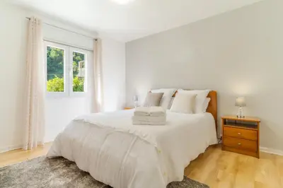 a white bedroom with a large bed and a window at Casa da Hortência do Faial in Faial