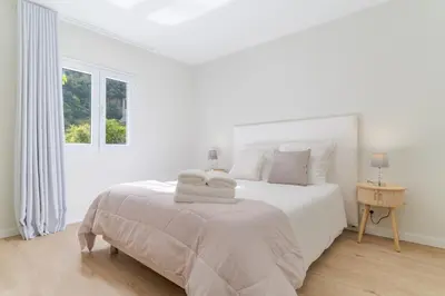 a white bedroom with a white bed with towels on it at Casa da Hortência do Faial in Faial