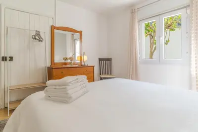 a white bedroom with a bed and a mirror at Casa da Hortência do Faial in Faial