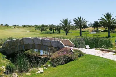 a stone bridge over a creek in a golf course at Apartamento Boavista in Lagos