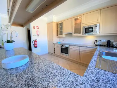 a kitchen with a granite counter top and a sink at Apartamento Boavista in Lagos