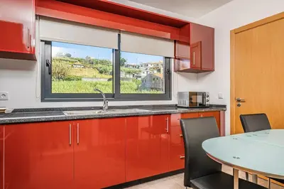 a kitchen with red cabinets and a window and a table at Canhas Residence II by Homie in Ponta do Sol