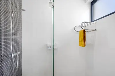 a shower with a glass door with a yellow towel at Recanto Dourado in Porto Santo