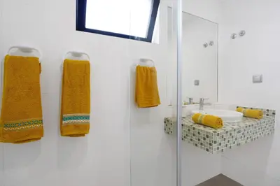 a white bathroom with yellow towels and a sink at Recanto Dourado in Porto Santo