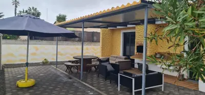 a patio with an umbrella and a table and chairs at Recanto Dourado in Porto Santo