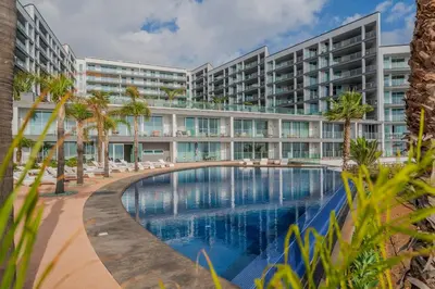 an exterior view of a large apartment building with a swimming pool at Madeira Palace III by An Island Apart in Funchal
