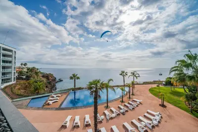 a view of a swimming pool with lounge chairs and the ocean at Madeira Palace III by An Island Apart in Funchal