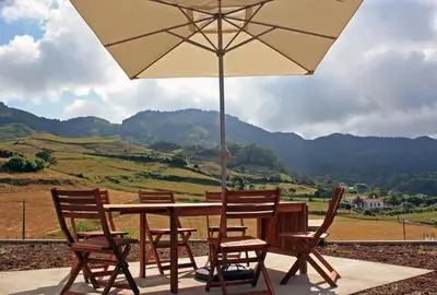 a wooden table with chairs and an umbrella at Casa de Almagreira - Empreendimento de Turismo em Espaço Rural - Casa de Campo in Vila do Porto