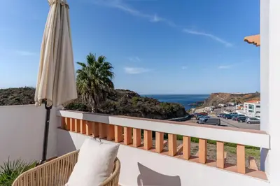 a balcony with an umbrella and a view of the ocean at Aloha Apartment Arrifana in Praia da Arrifana